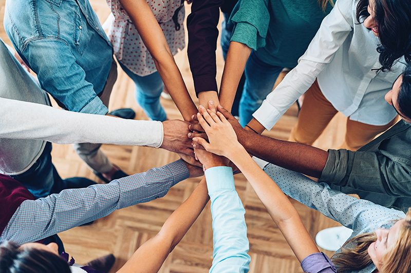 group of people putting their hands together in a circle